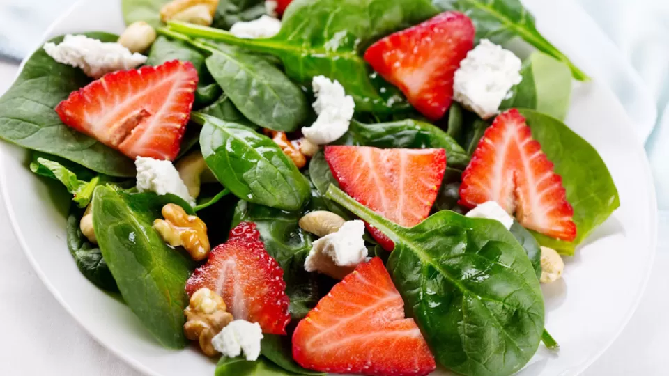 Fresh strawberries scattered in a bed of spinach.