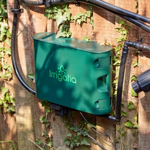 Woman using the SOL C120 irrigation kit to water a tomato plant